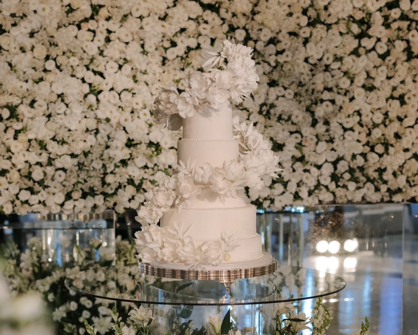 Bolo branco diante de um muro de rosas