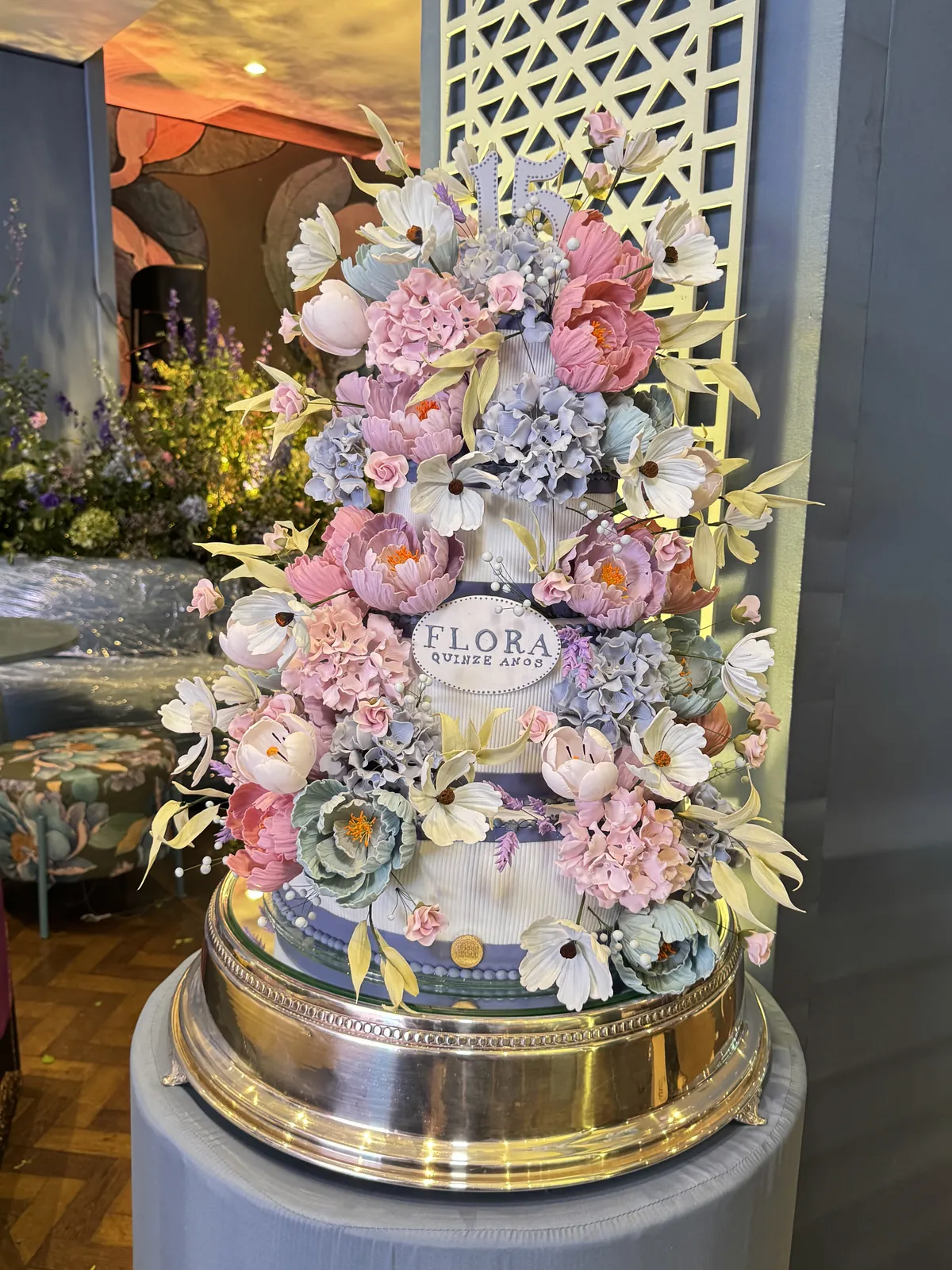 Bolo alto coberto de flores de açúcar em tons de rosa, azul e verde