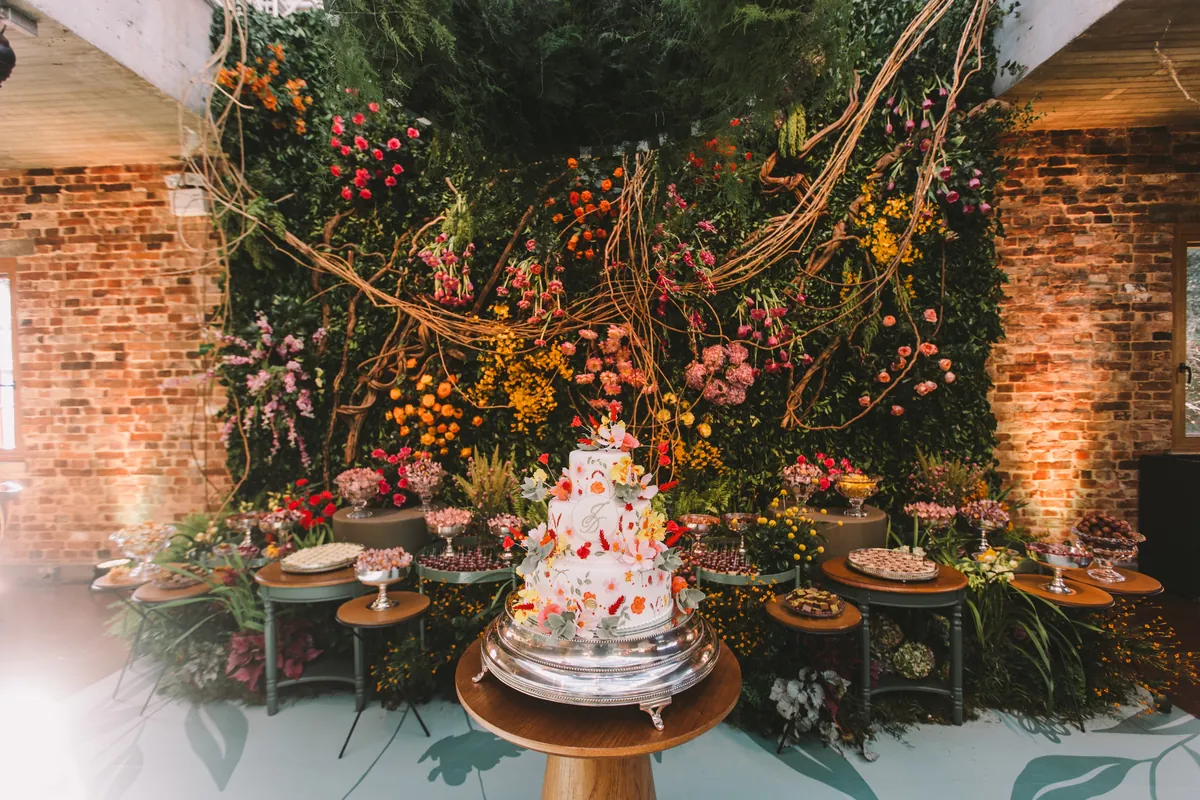Bolo florido em meio à decoração de flores e folhagens