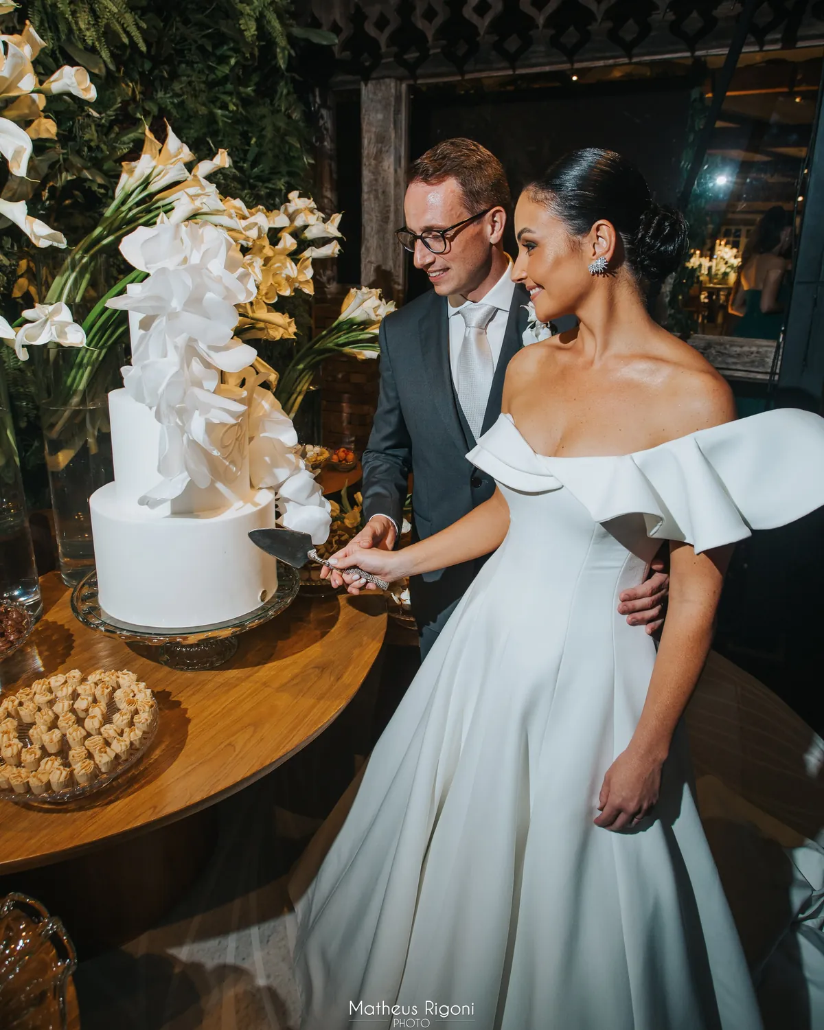Noivos cortando o bolo branco com orquídeas